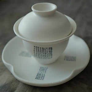 White ceramic gaiwan with lid on a matching saucer.