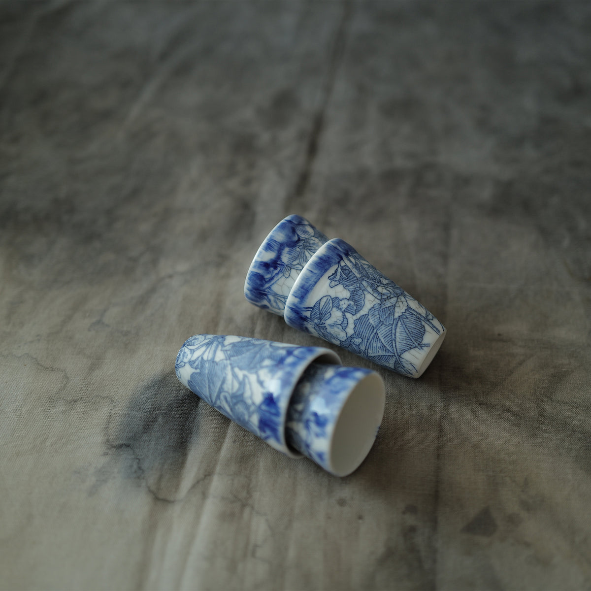 Four blue and white ceramic teacups on a textured surface.