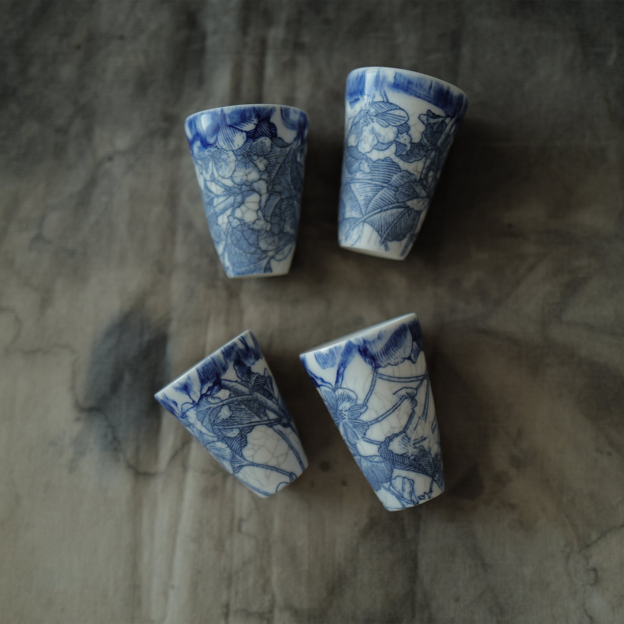 Four blue and white ceramic teacups on a textured surface